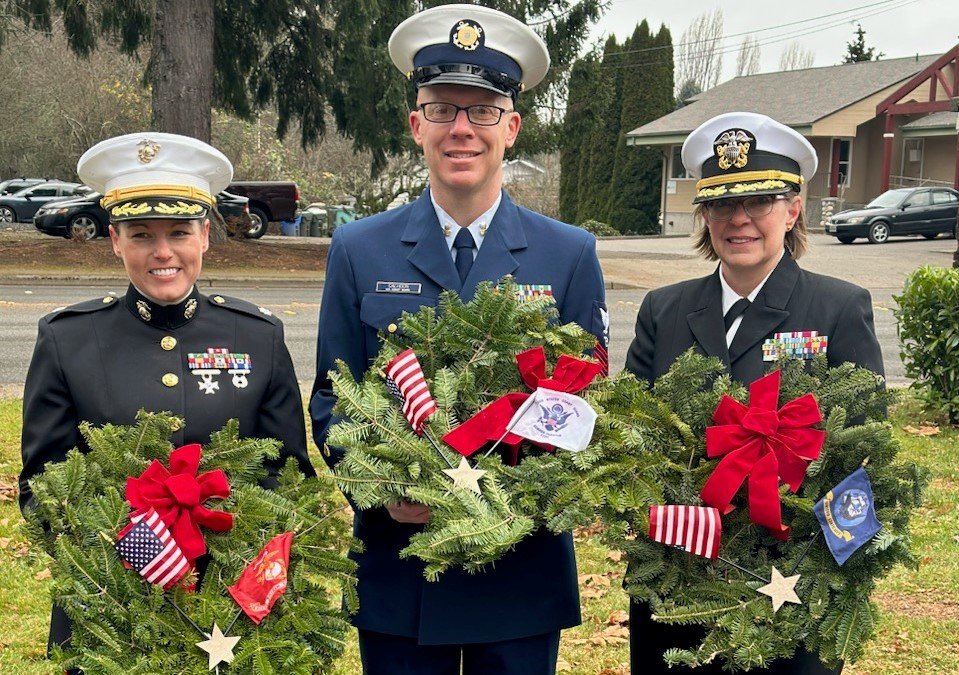 Three officers in uniform with wreaths: Lieutenant Colonel Rachel Gonzales of the US Marine Corps; Petty Officer Scott Calhoon of the US Coastguard; Captain Liz Dykstra of the US Navy Reserves.